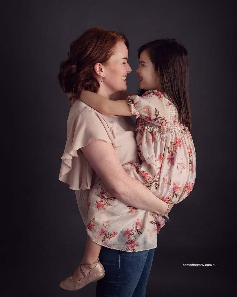 mother holding older daughter facing each other smiling