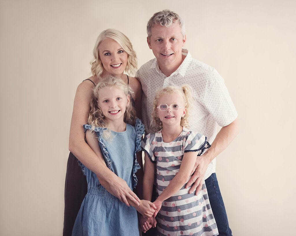 family of mother, father, two sisters all smiling to camera