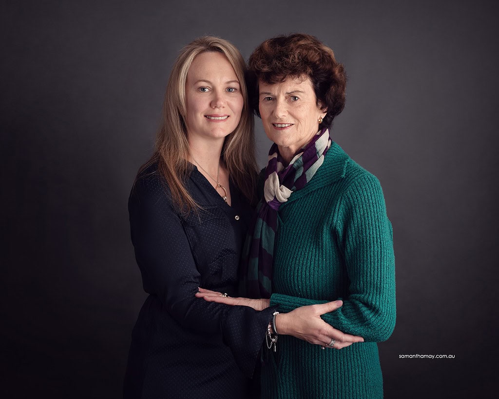 mother and her adult daughter embracing, both smiling to the camera
