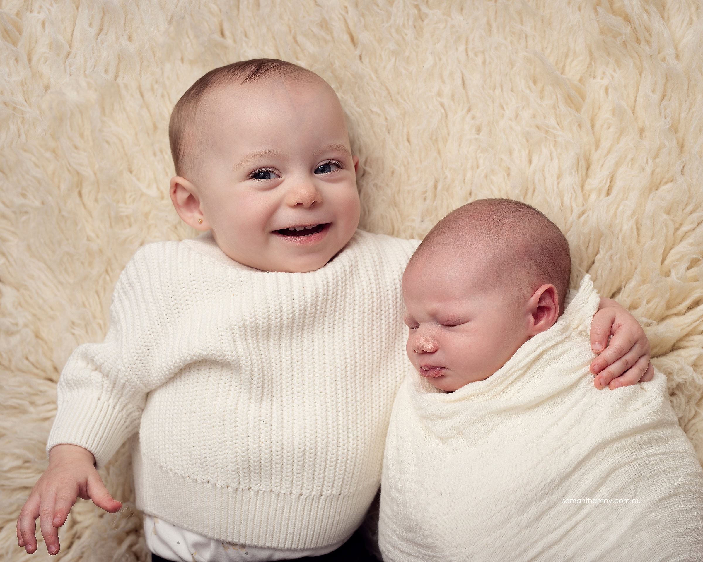 happy toddler cuddling baby brother